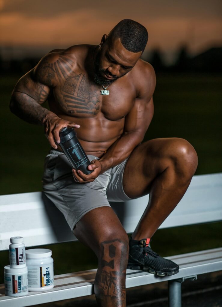 Muscular Man Sitting on a Bench and Holding a Bottle