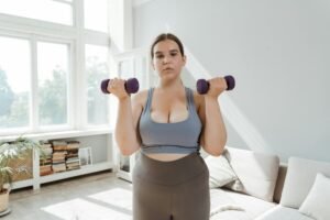 A plus size woman exercises with dumbbells at home, promoting body positivity and wellness.